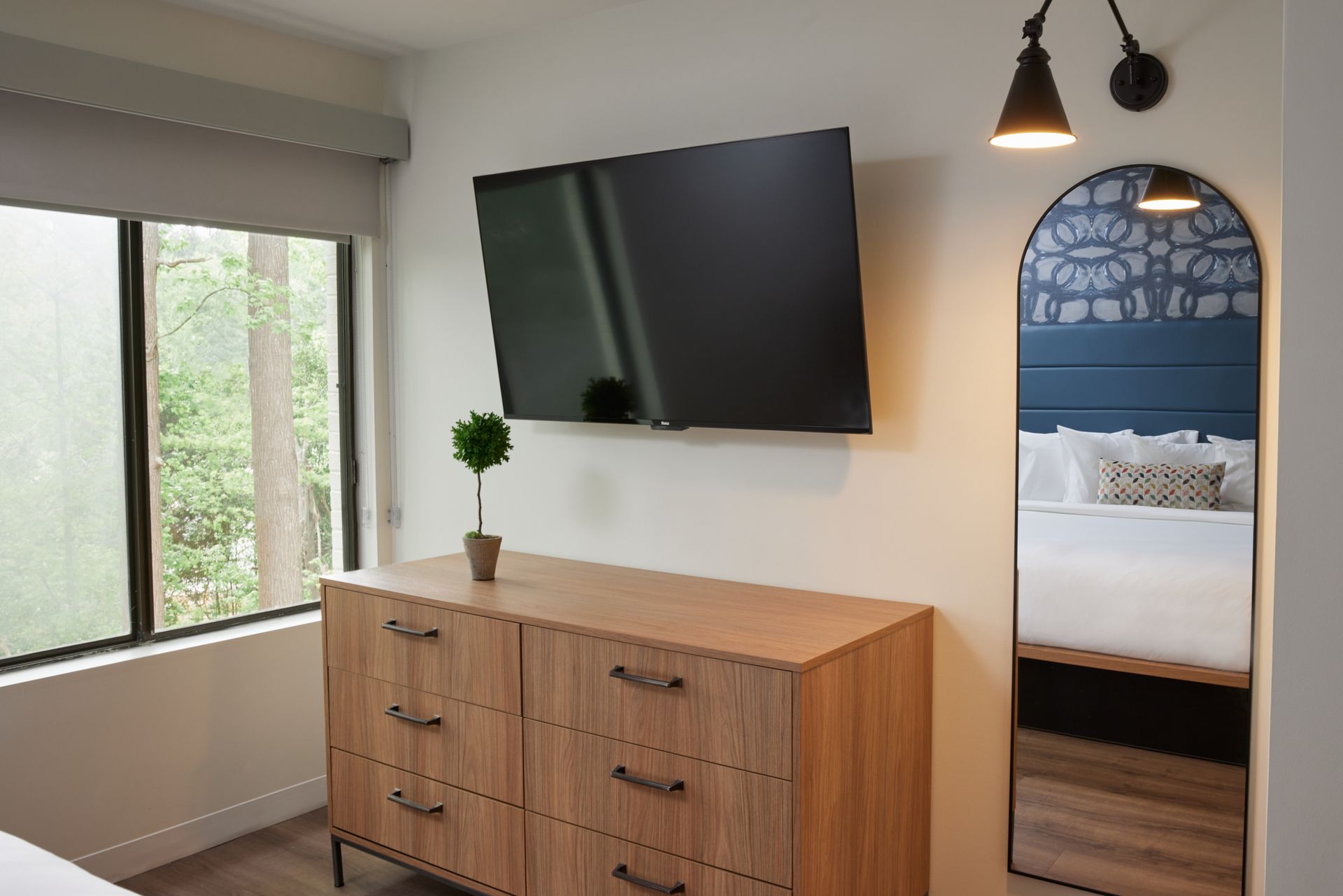 A hotel room with a dresser , television , and mirror.