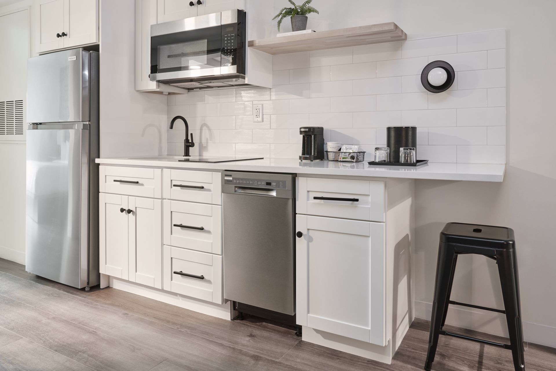 A kitchen with white cabinets , stainless steel appliances , a refrigerator and a microwave.