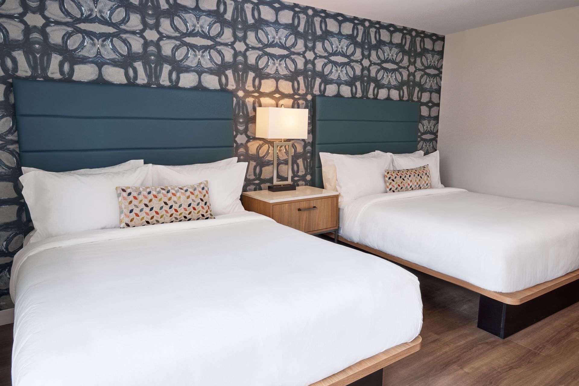 A hotel room with two beds and a nightstand.