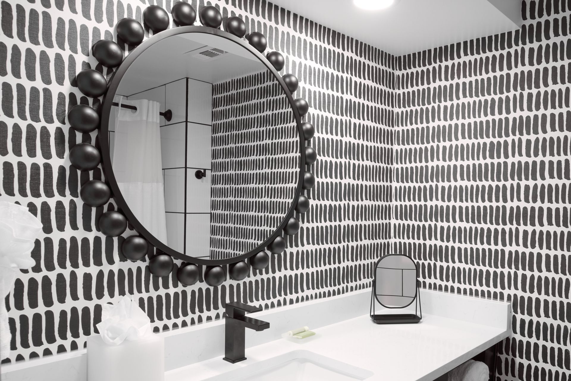 A bathroom with a round mirror and a sink.
