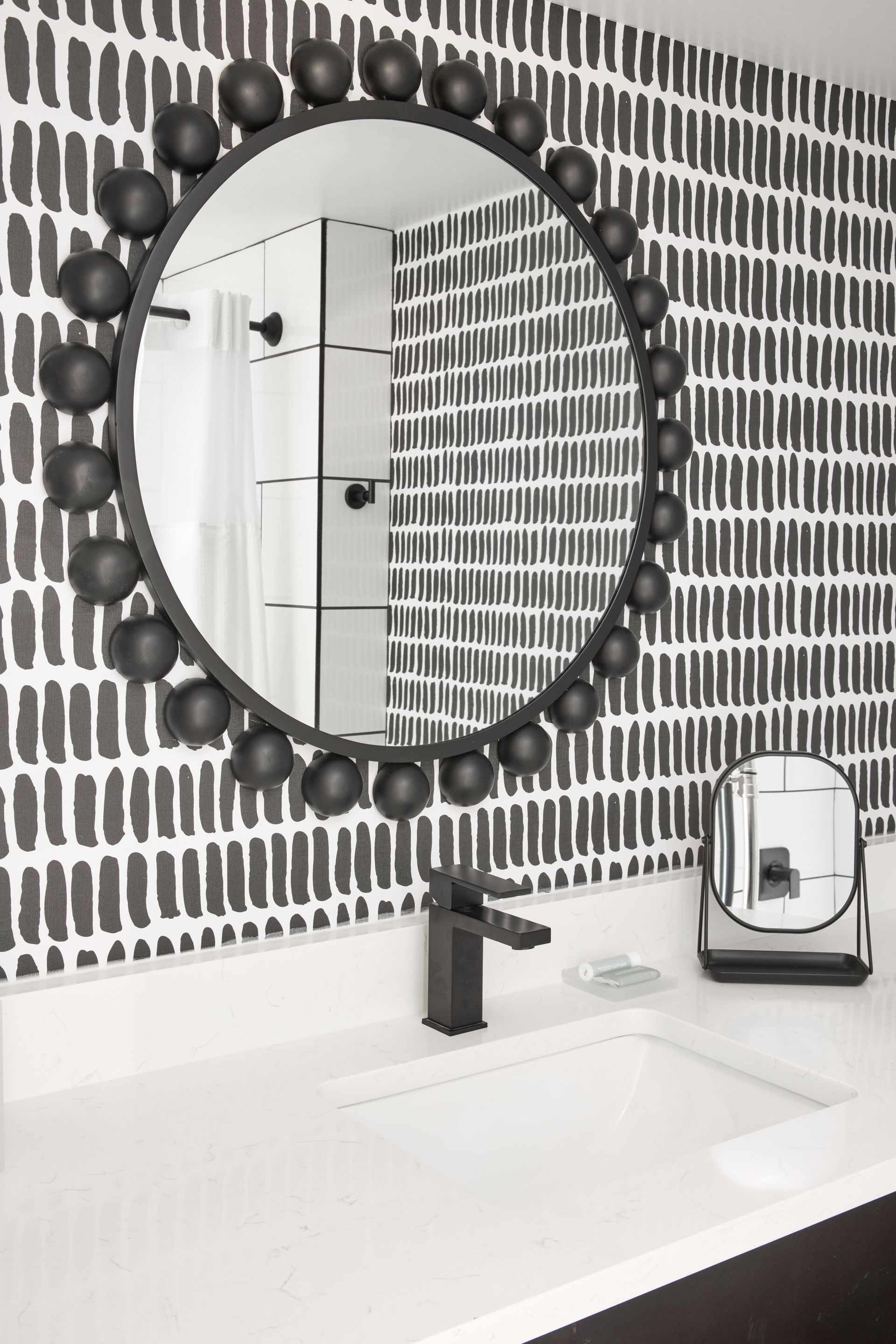 A bathroom with a round mirror and a sink.