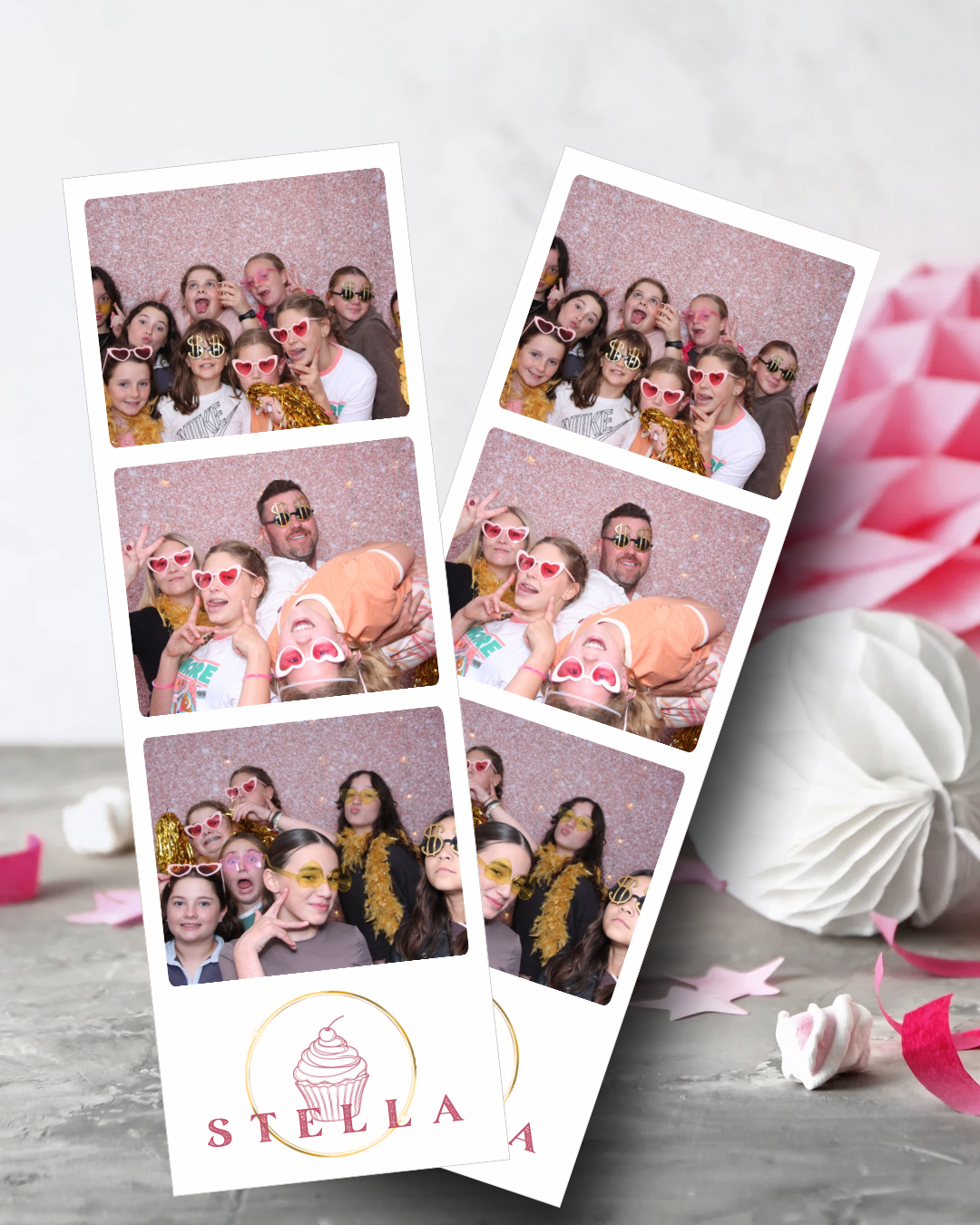 Photo booth strips with multiple candid shots of a group with heart-shaped glasses. Pink glitter background.