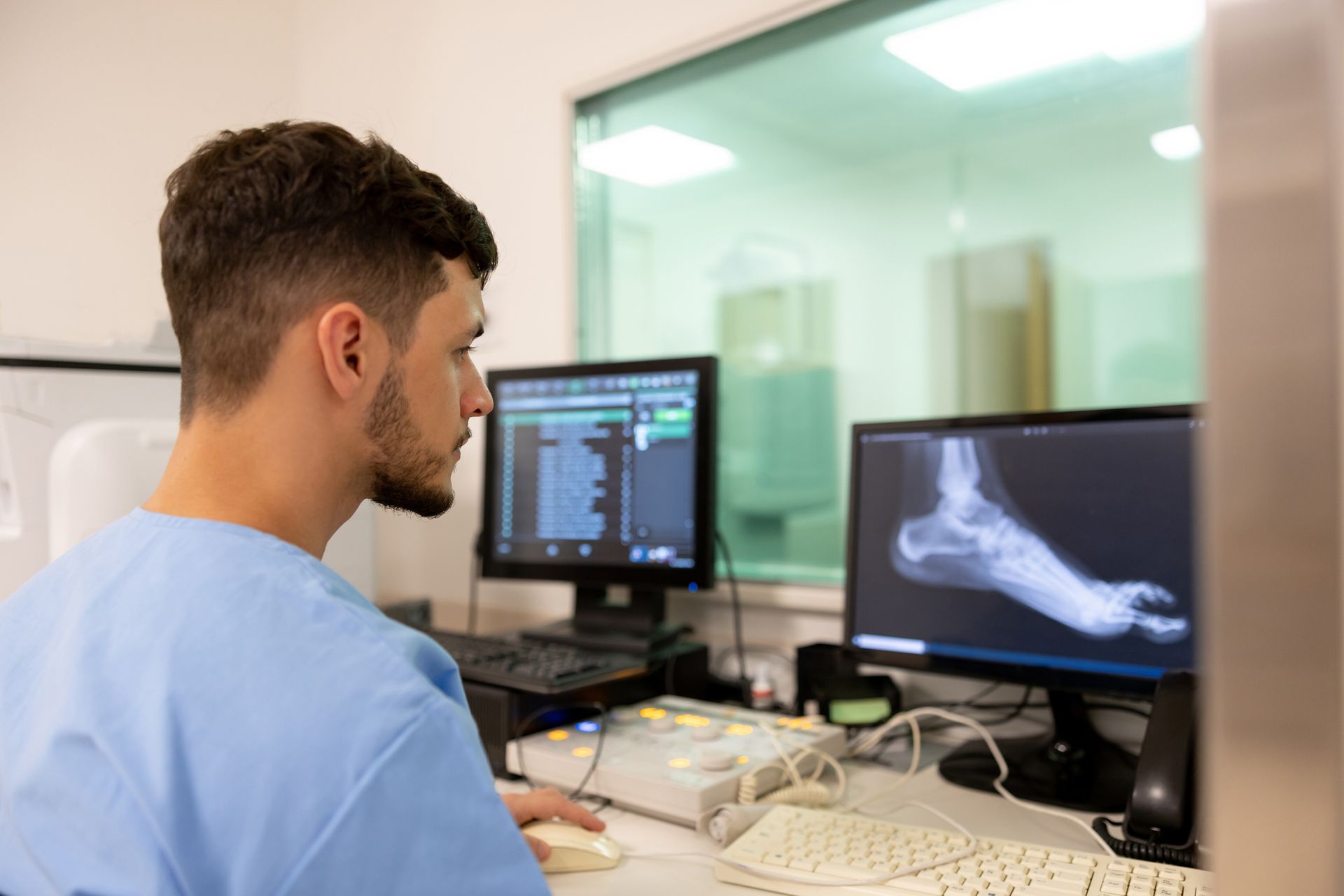A man is looking at an x-ray of a foot on a computer screen.