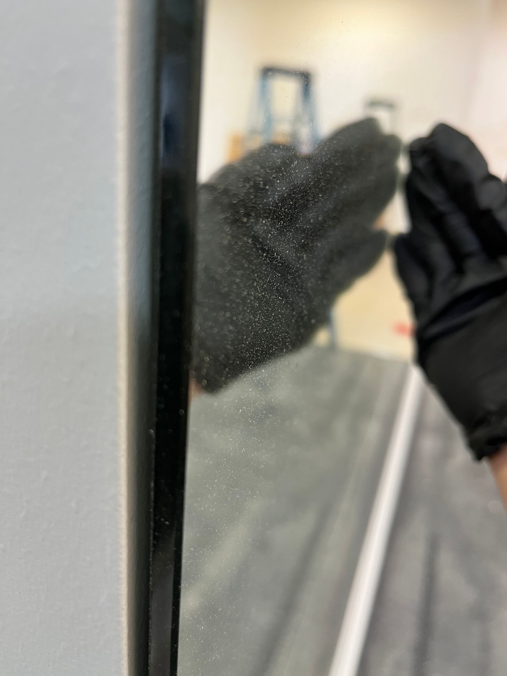 A person is cleaning a mirror with a glove.