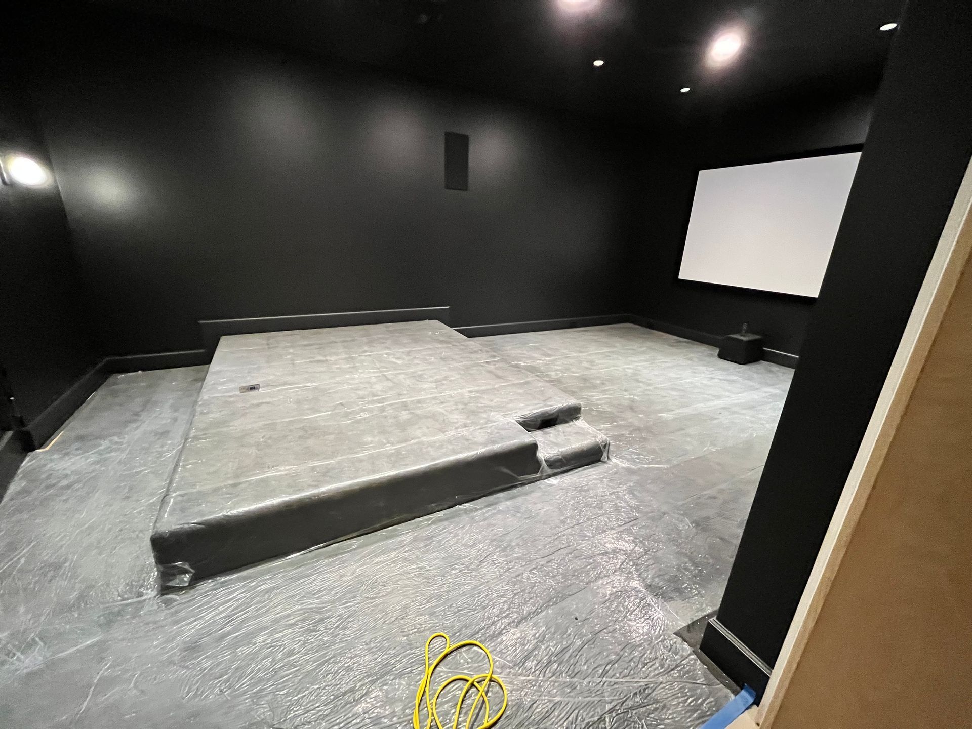 A room with a projector screen and a concrete floor