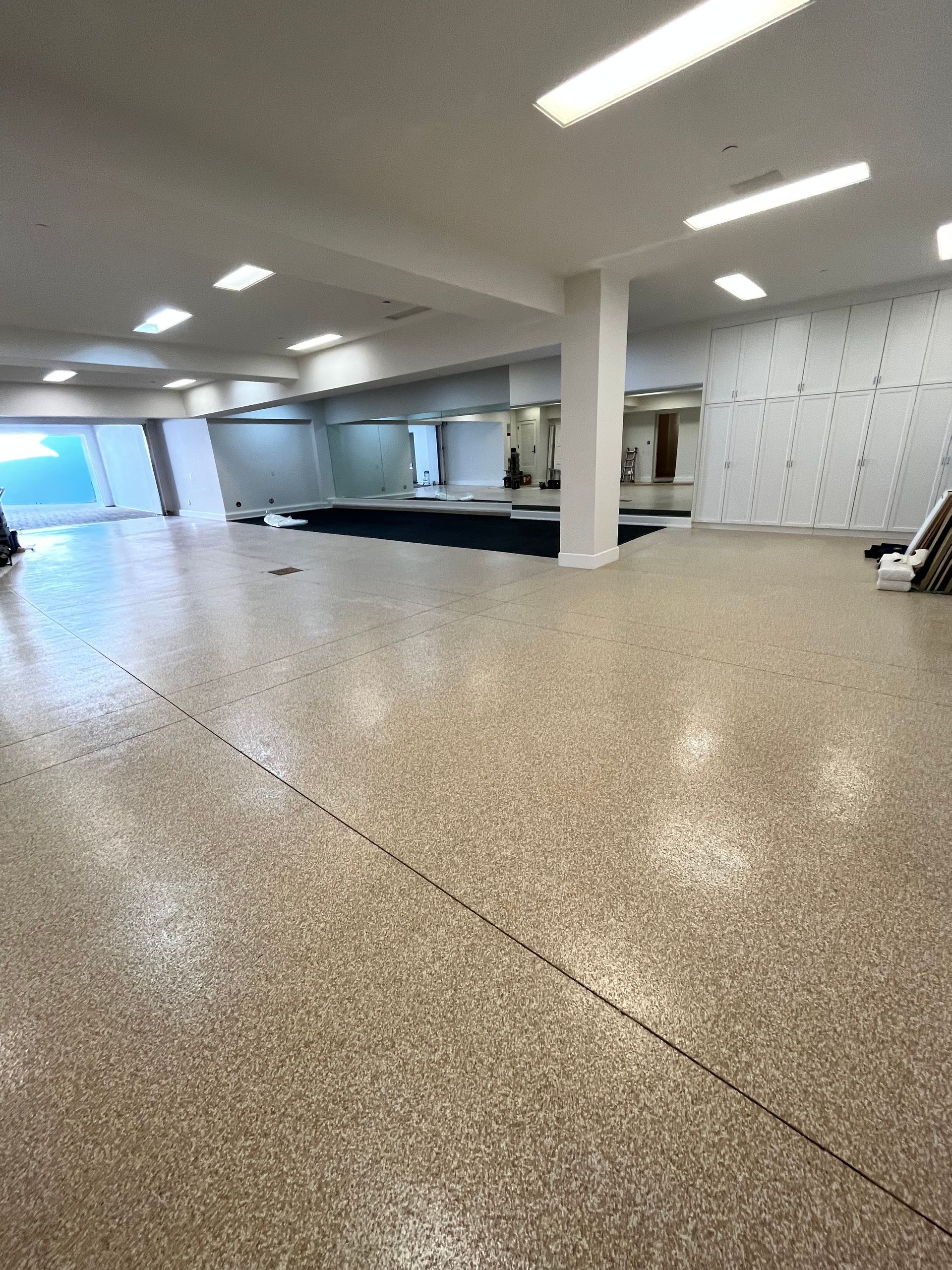 A large empty room with a concrete floor and a white wall.