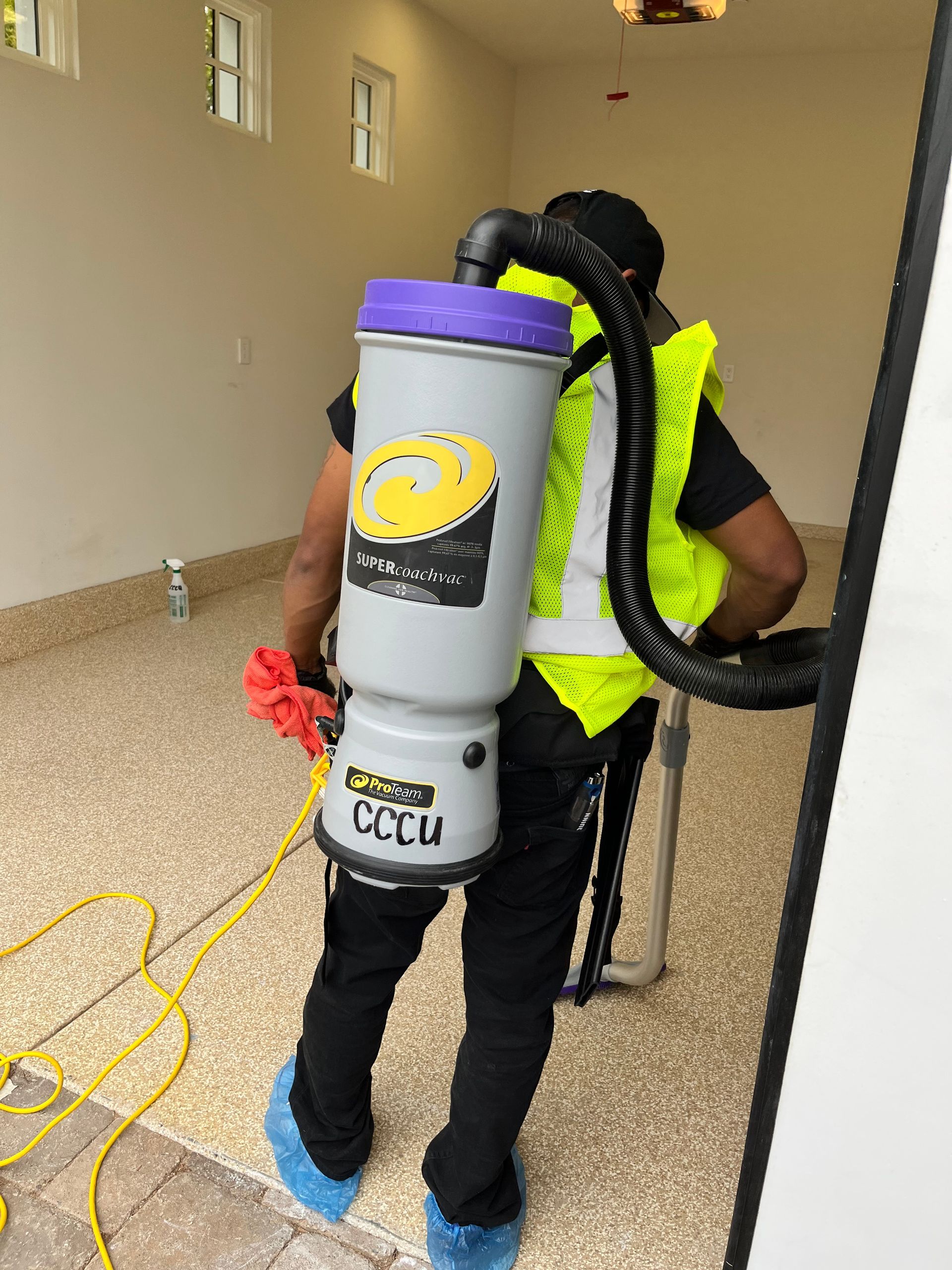 A man is carrying a vacuum cleaner on his back.