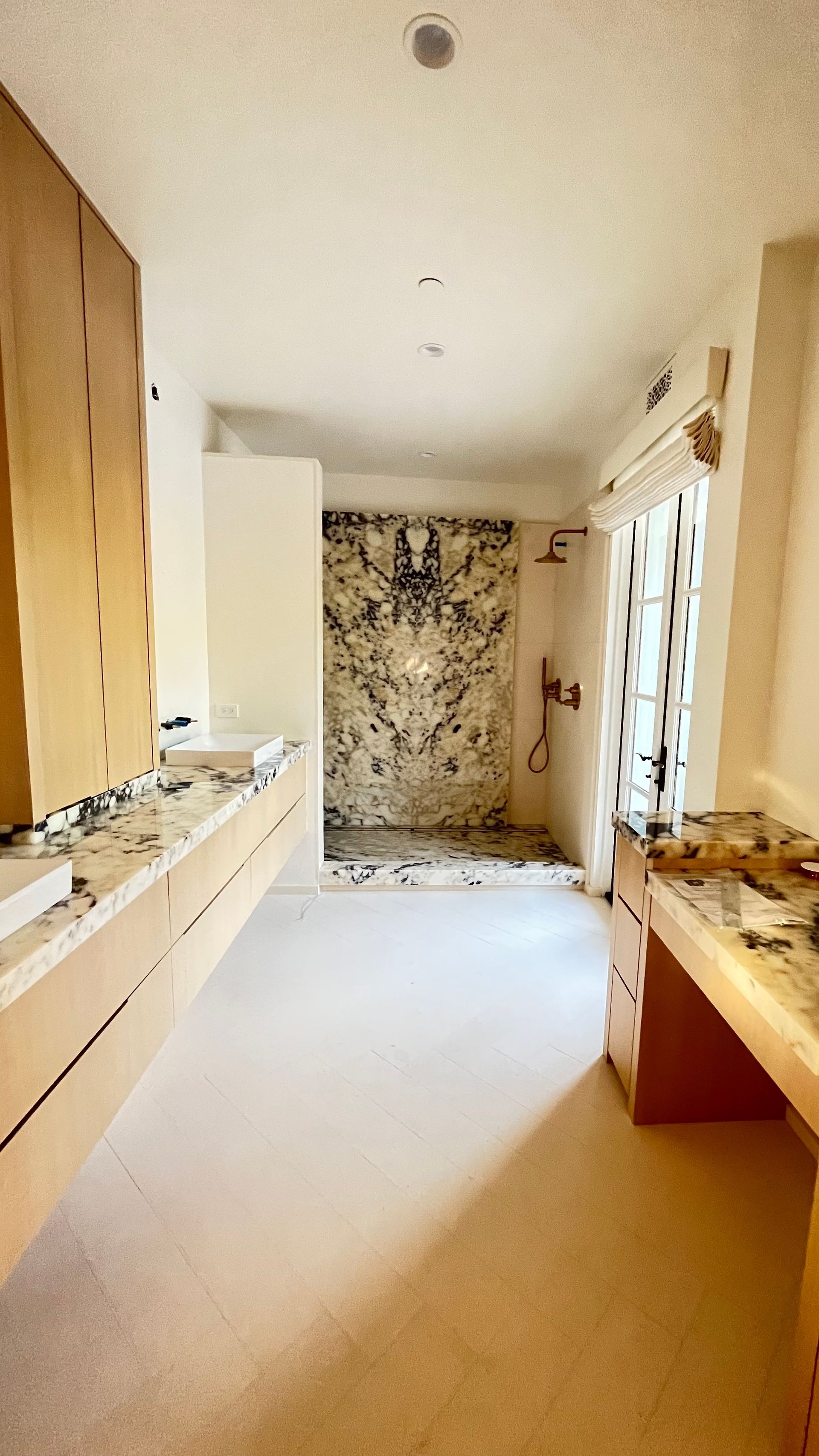 A bathroom with two sinks and a walk in shower.