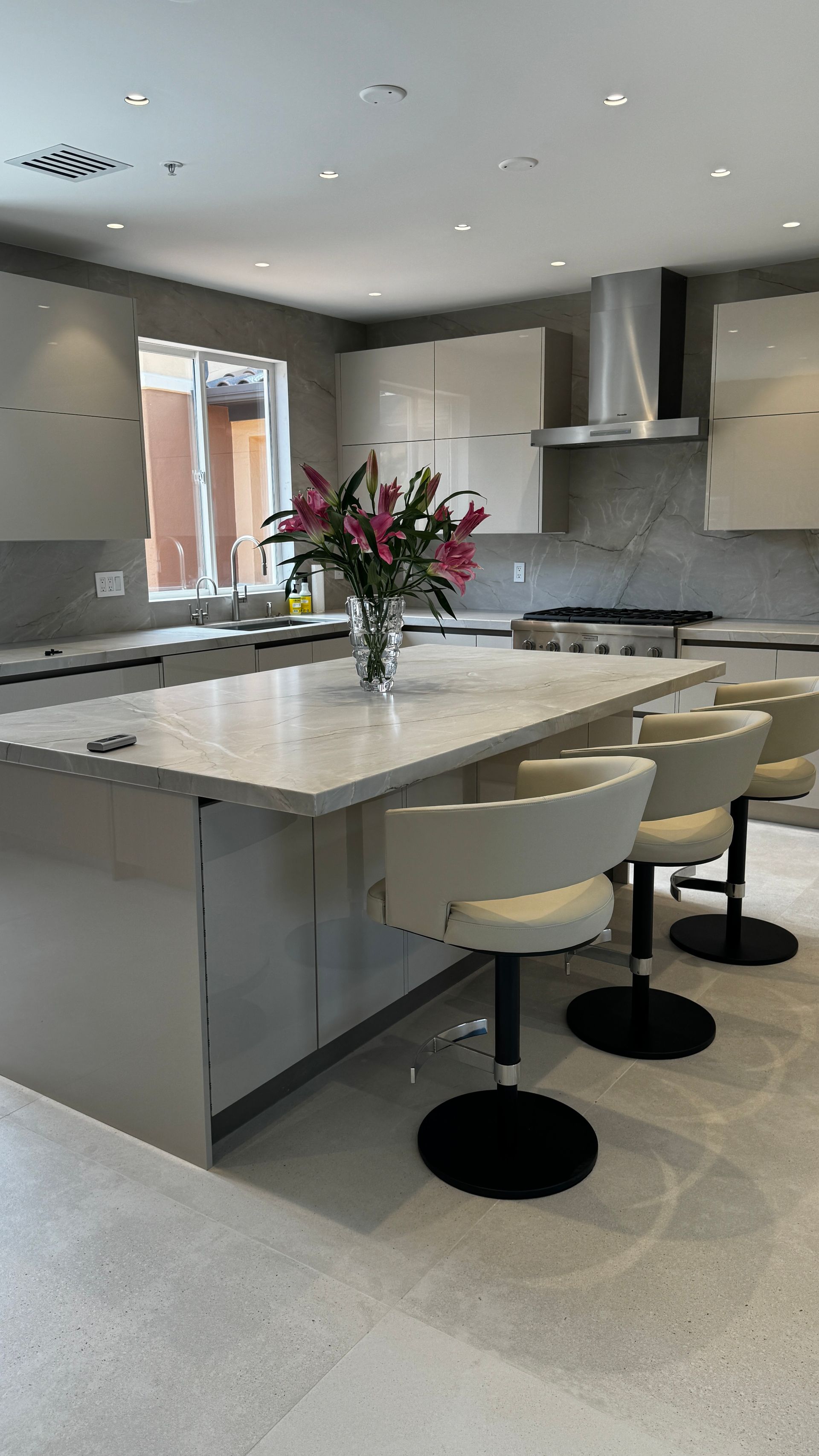 There is a vase of flowers on the counter in the kitchen.