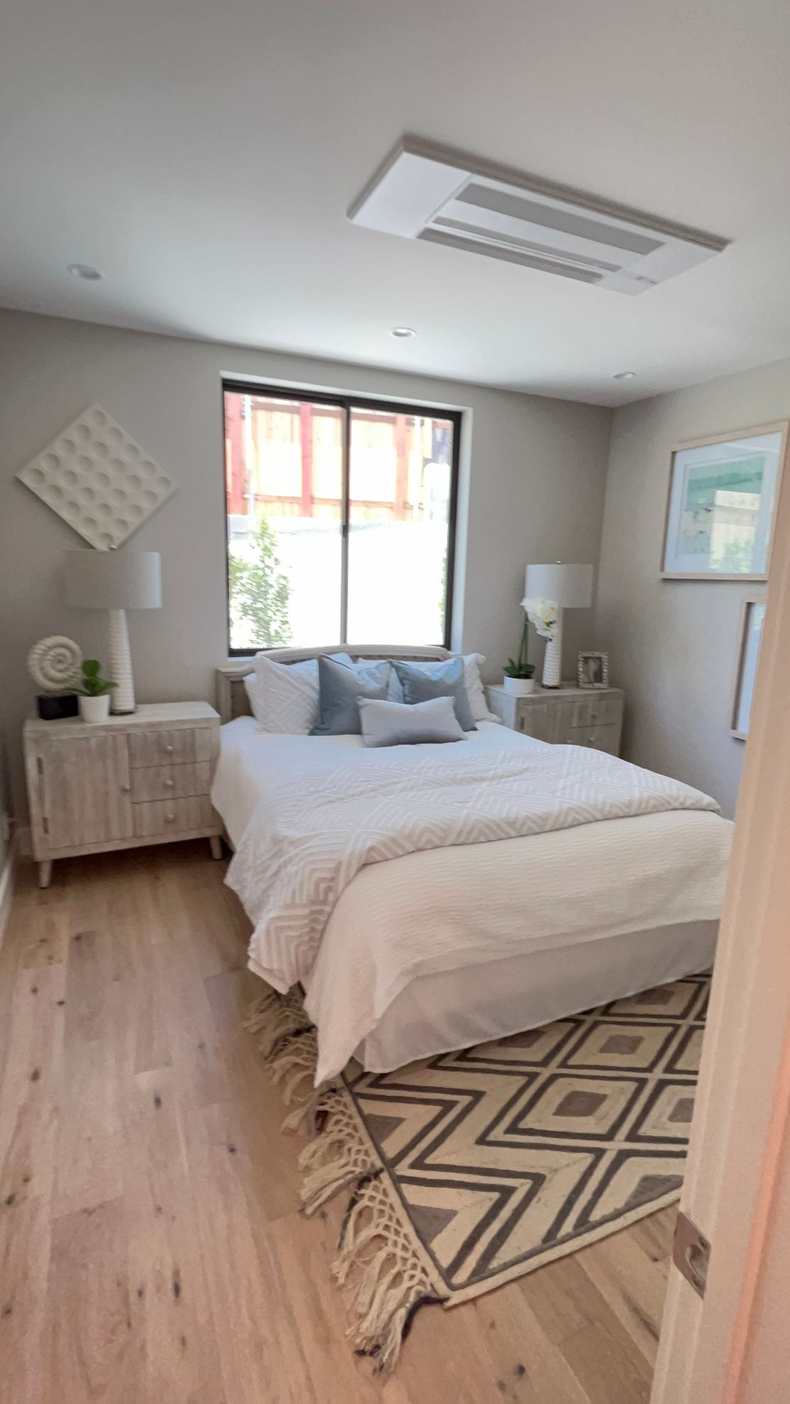 A bedroom with a bed , nightstand , rug and window.