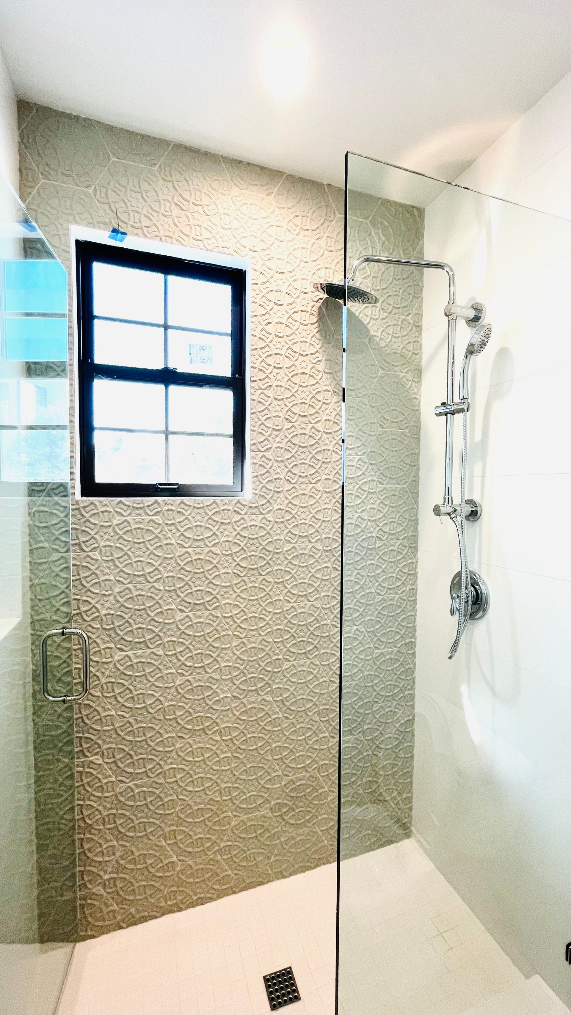 A bathroom with a walk in shower and a window.