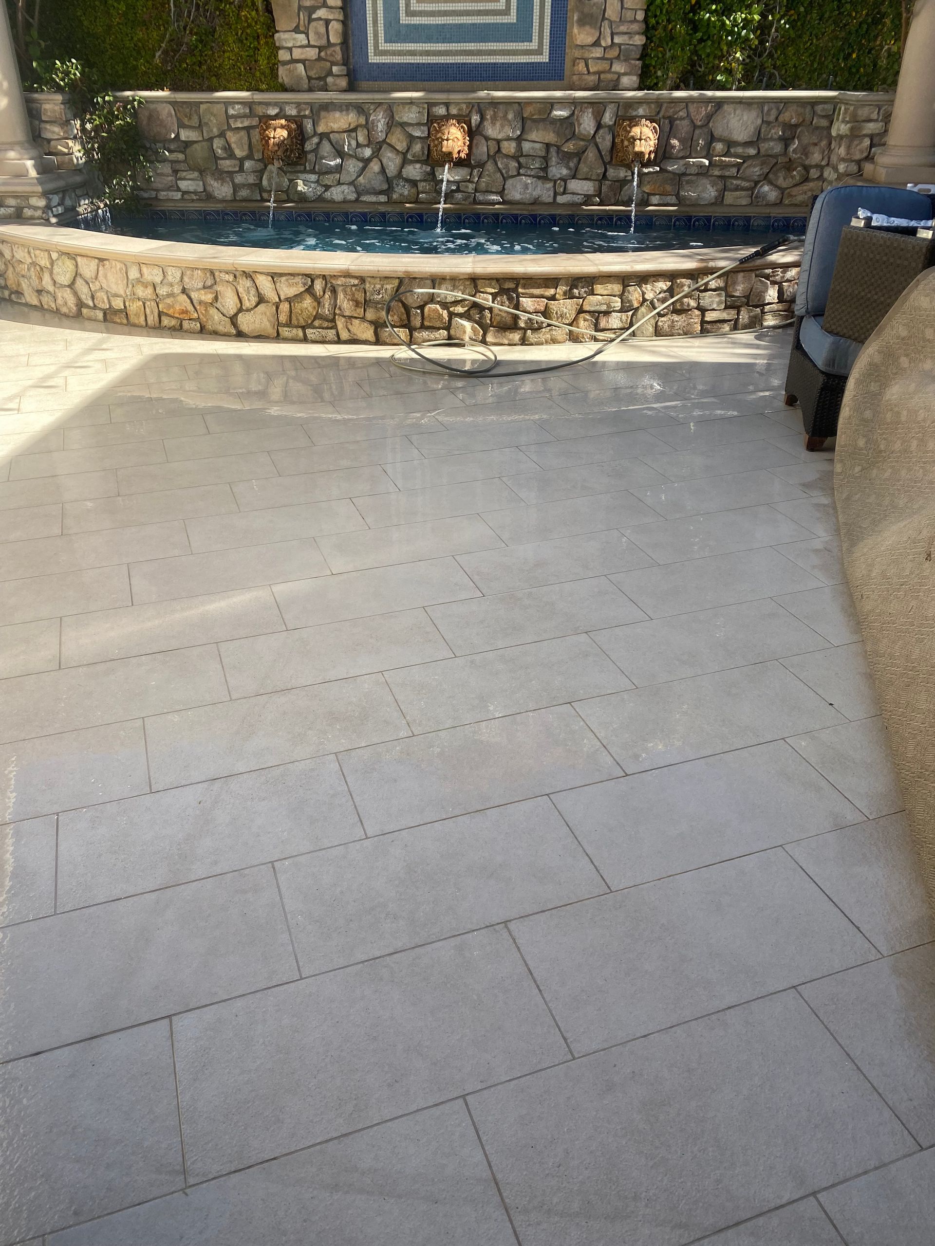 A patio with a stone wall and a fountain in the background