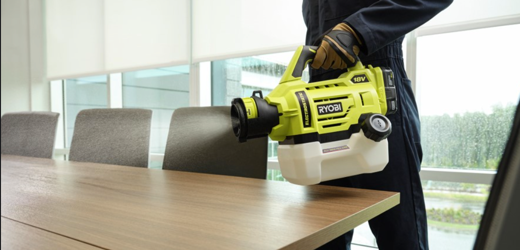 A man is standing in an empty room with a vacuum cleaner on his back.