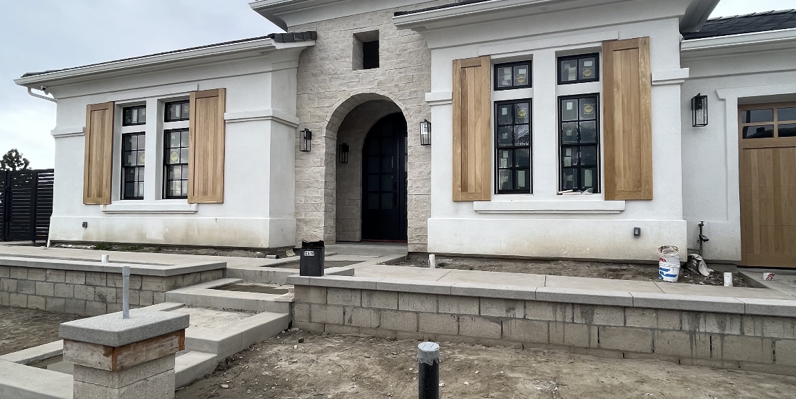 A white house with wooden shutters on the windows is being built.