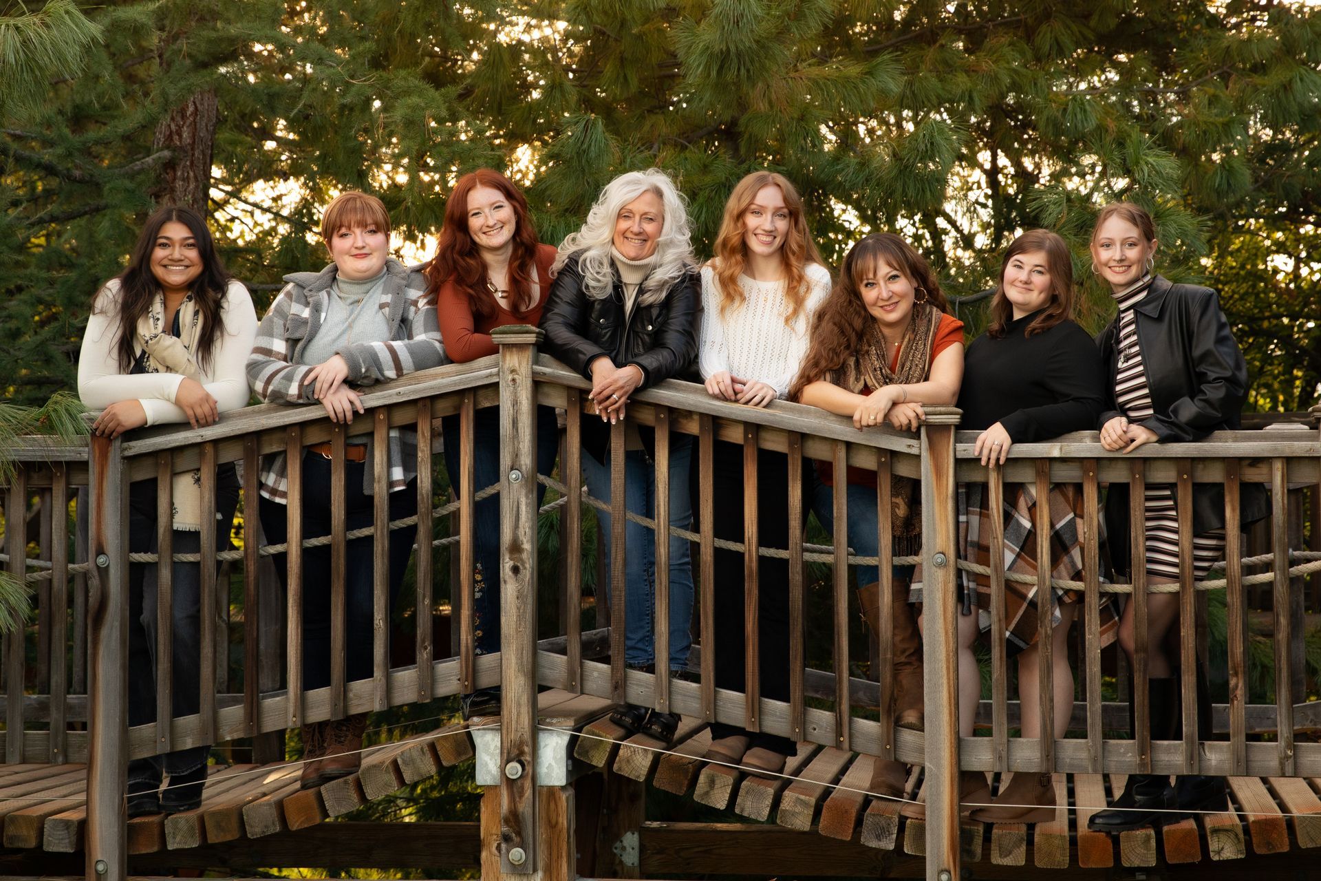 Group of eight women standing on a bridge.