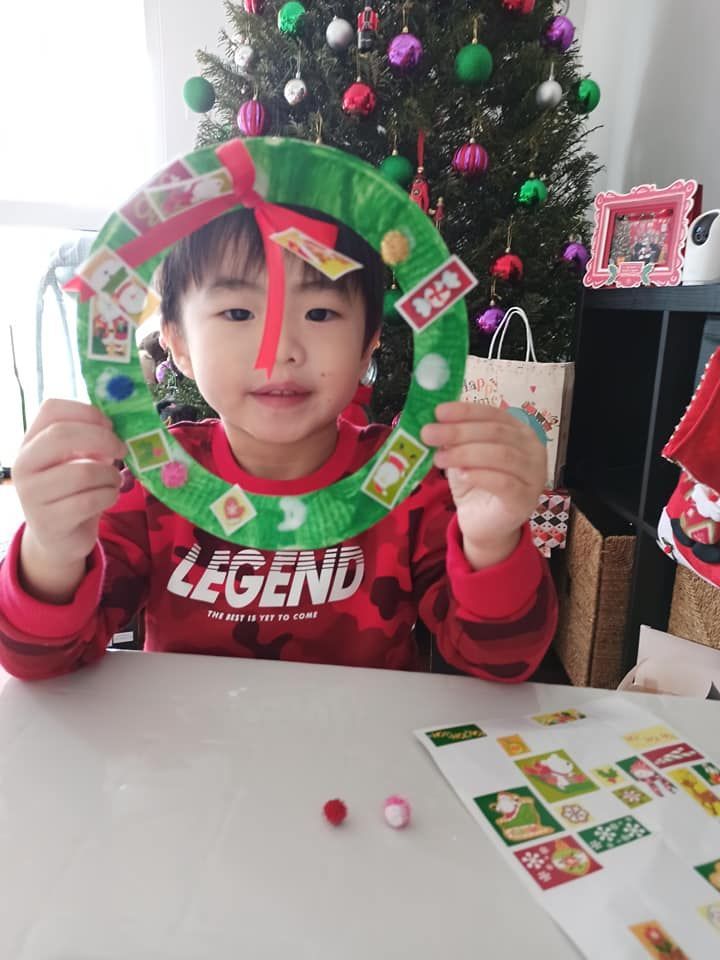 A little boy wearing a legend shirt is holding a paper wreath