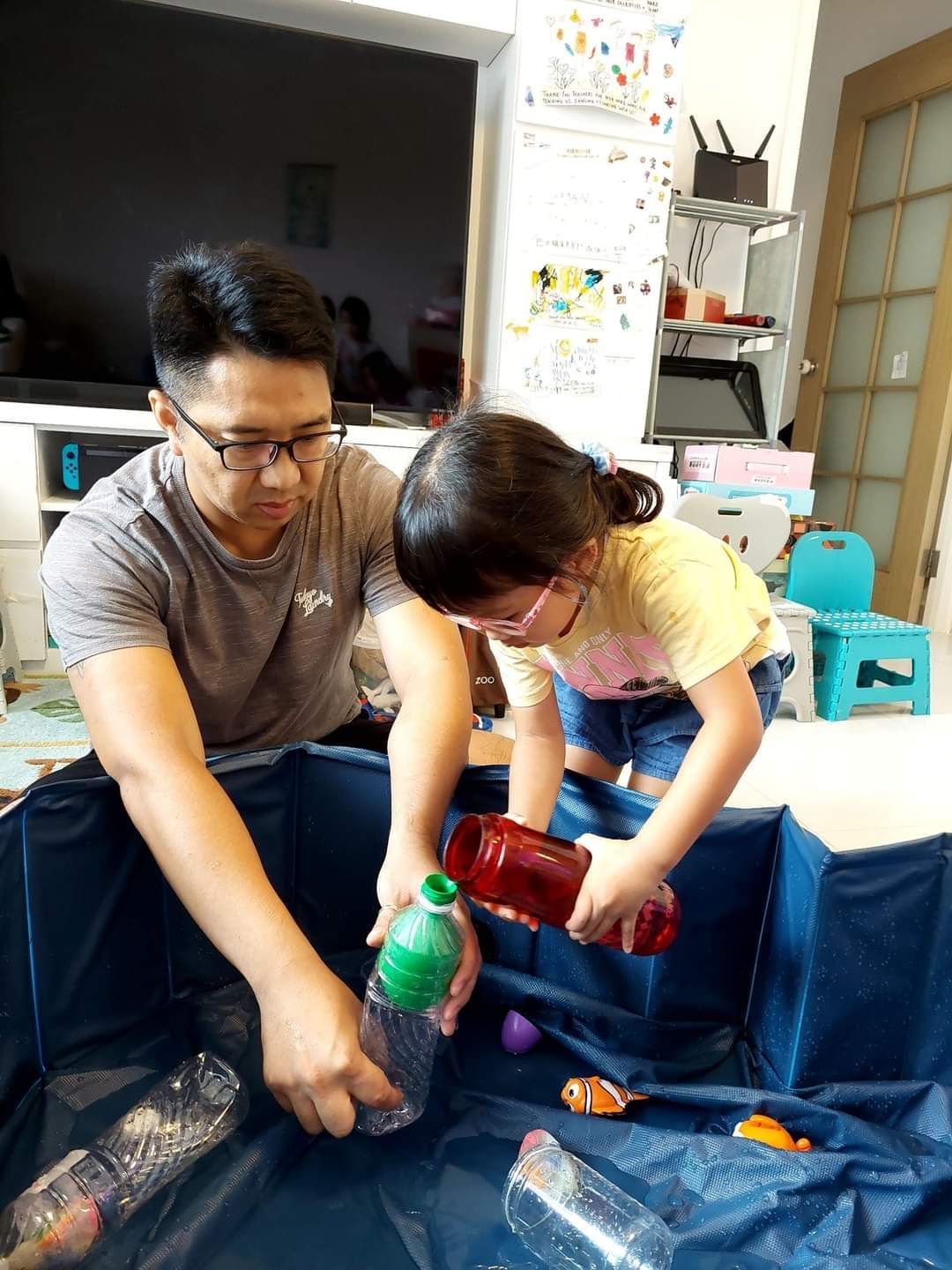 A man and a little girl are playing in a pool of water.