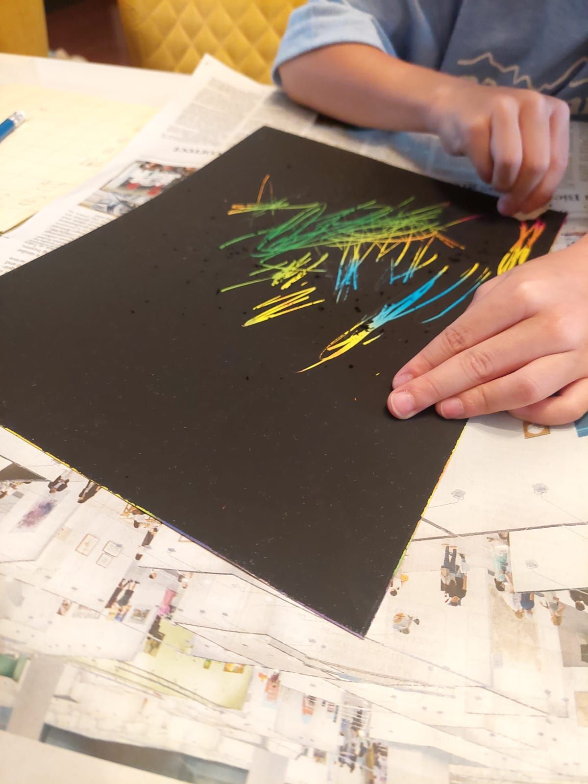 A person is drawing on a piece of black paper