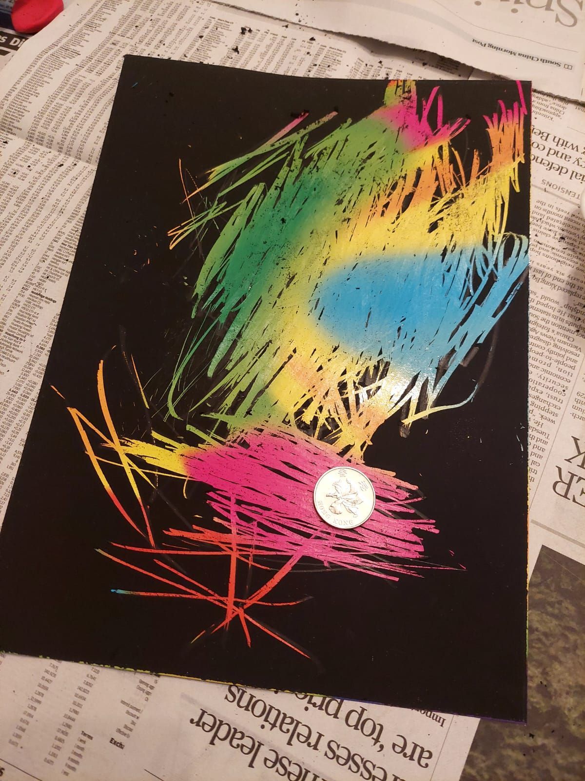 A colorful drawing on a piece of paper with a coin in the middle