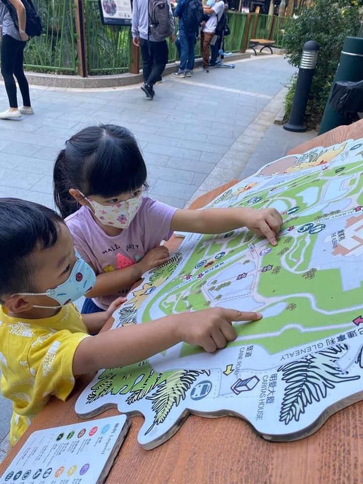 A boy and a girl wearing masks are looking at a map.