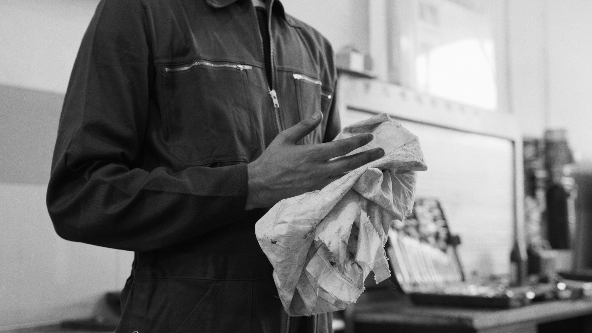 A man is cleaning his hands with a towel in a black and white photo.