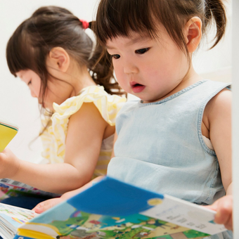 Two Young Sisters Looking At Picture Books — Raleigh, NC — Pamela's Daycare Center