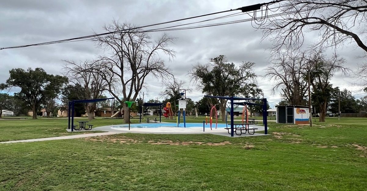 A park with a swimming pool and a playground on a cloudy day.