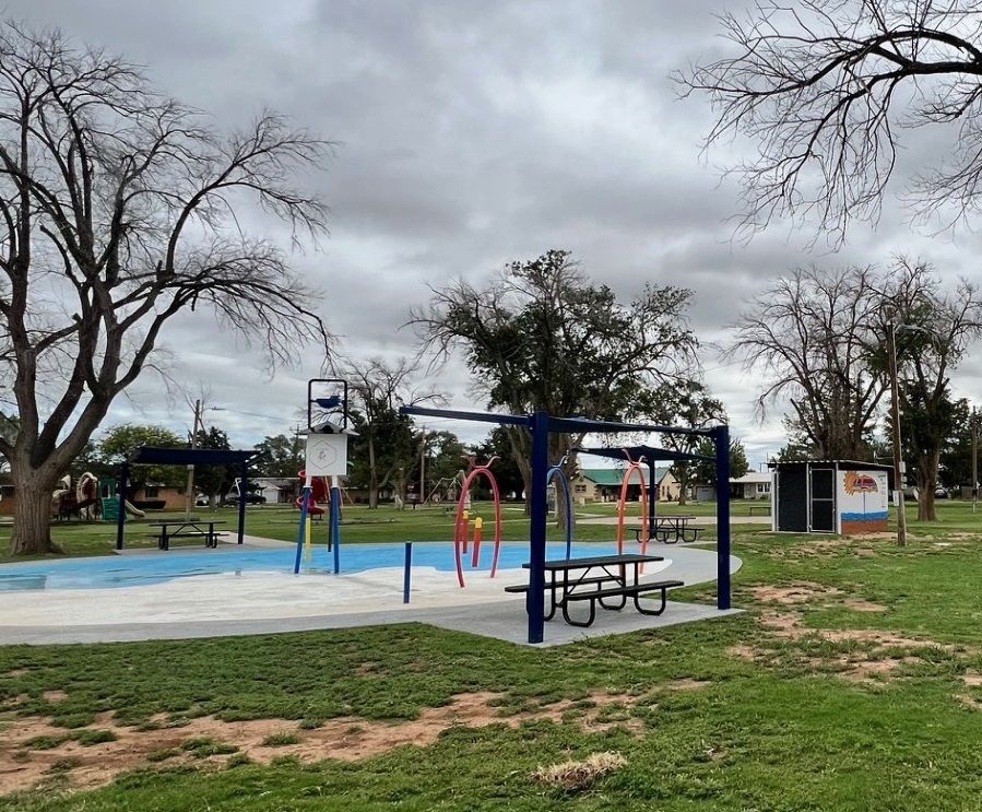 A playground in a park with a basketball hoop and swings