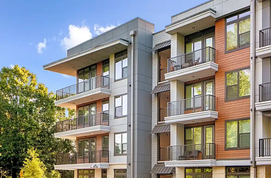 A large apartment building with cars parked in front of it.