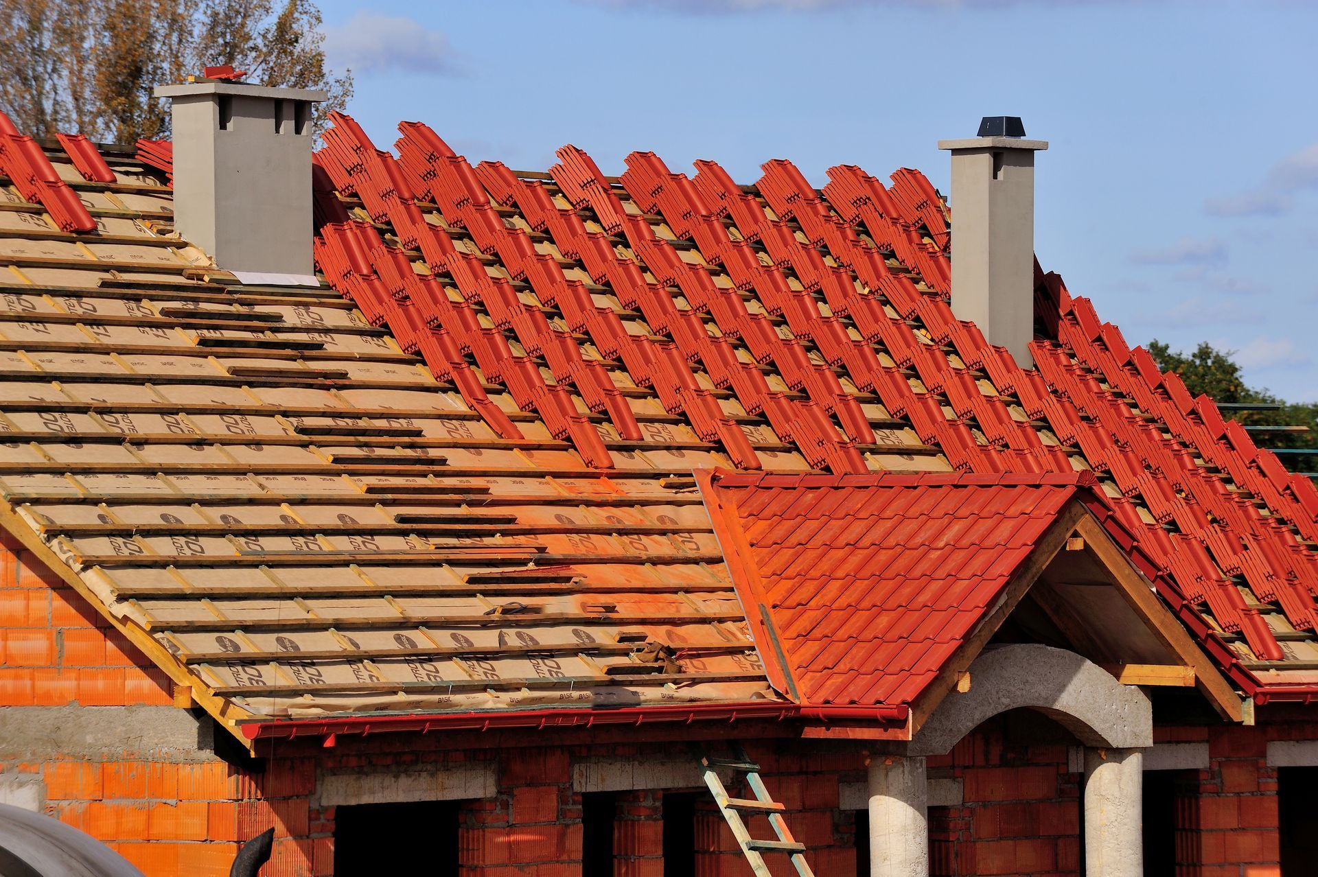 The roof of a house is being built with red tiles.