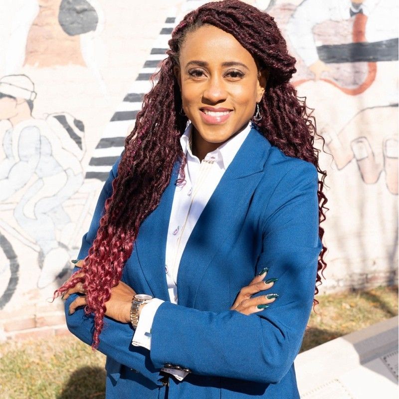 Woman in camo uniform smiles at child at table. Kitchen setting.