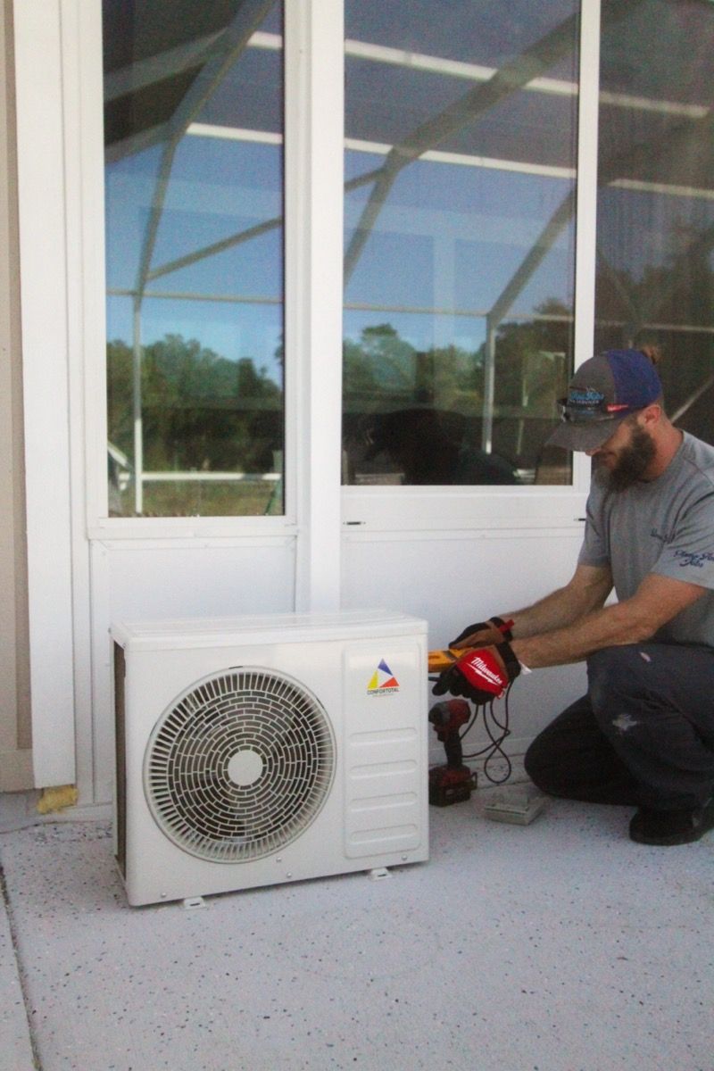 A man is installing an air conditioner on a porch - Milton, FL - Damn Fine Jobs