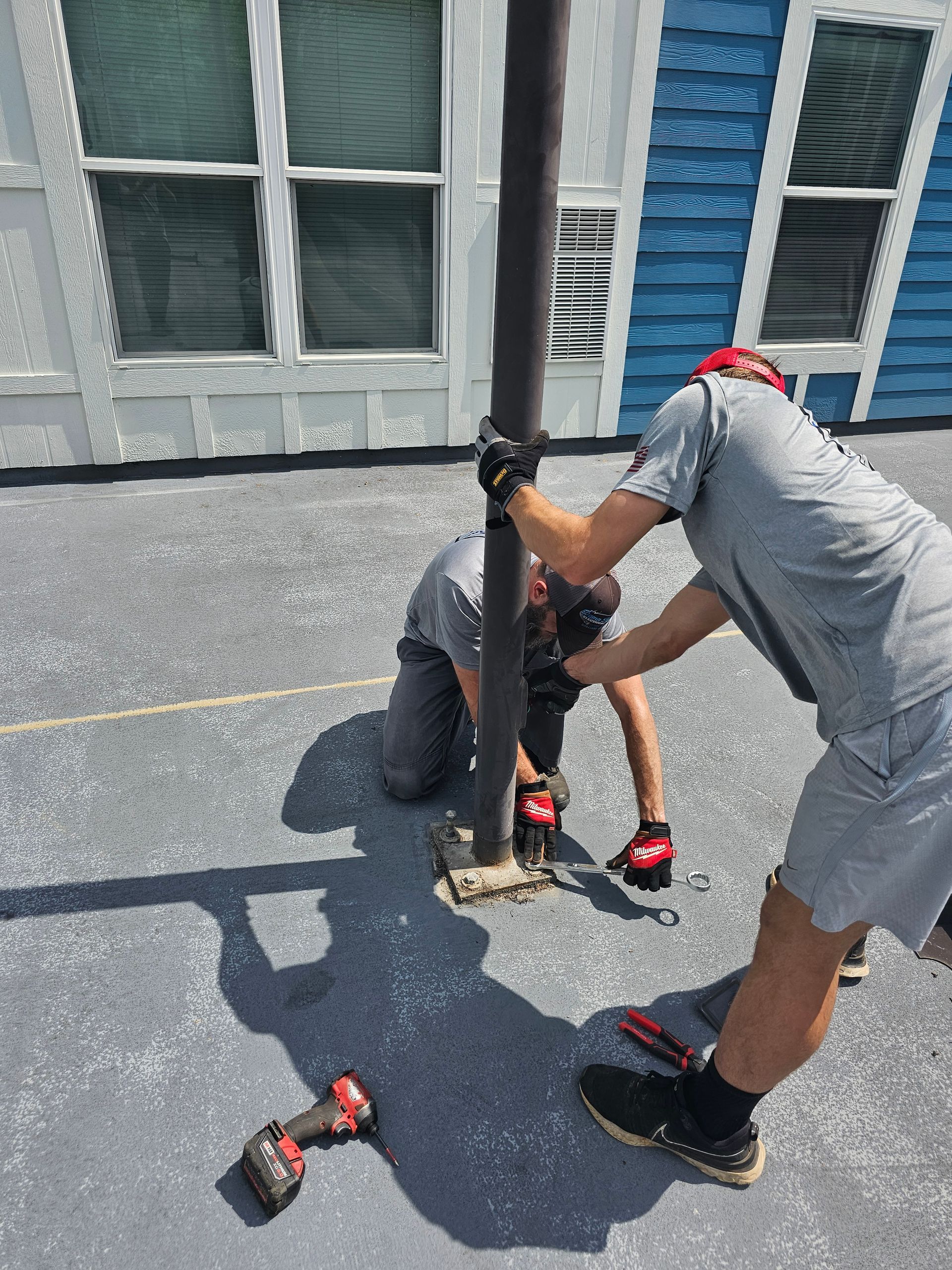 Two men are working on a pole on a roof - Milton, FL - Damn Fine Jobs