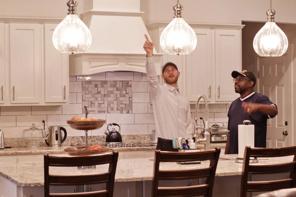 Two men are standing in a kitchen looking at a light fixture - Milton, FL - Damn Fine Jobs