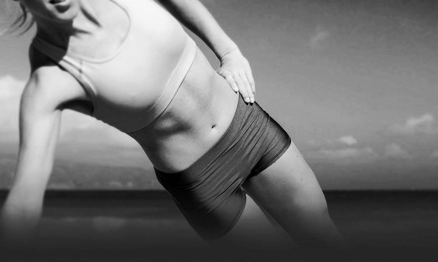 black and white closeup photo of slim woman's wearing workout clothes exposing her flat abdomen