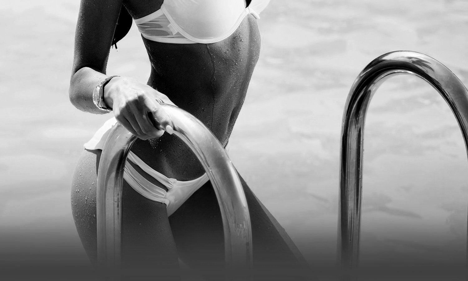 black and white closeup photo of a woman's abdomen as she exits swimming pool wearing a white bikini