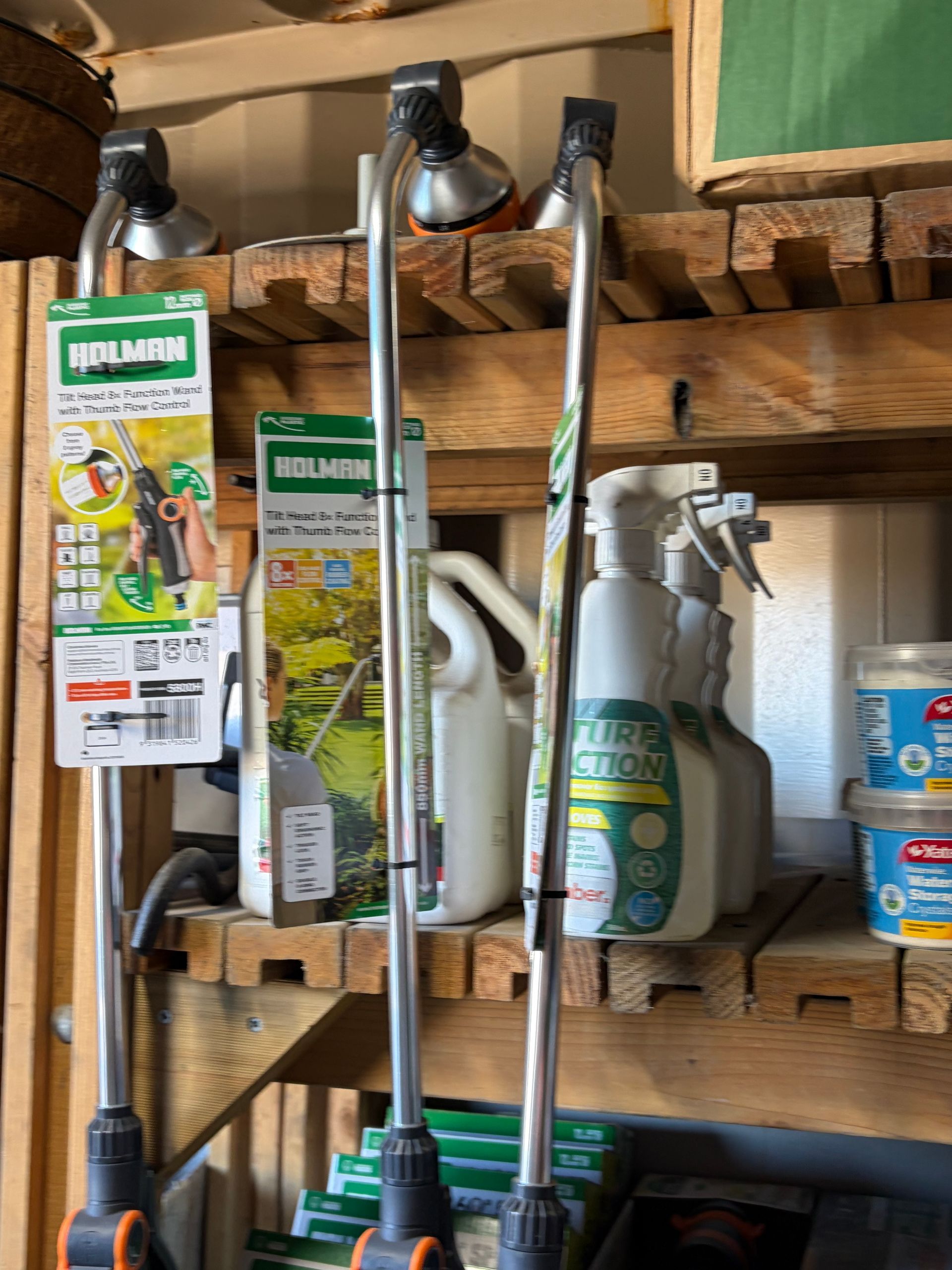 Shelves with gardening tools and plant spray bottles in a garage or shed.