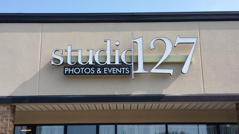 Storefront sign reading “studio 127 PHOTOS & EVENTS” on a beige building facade.