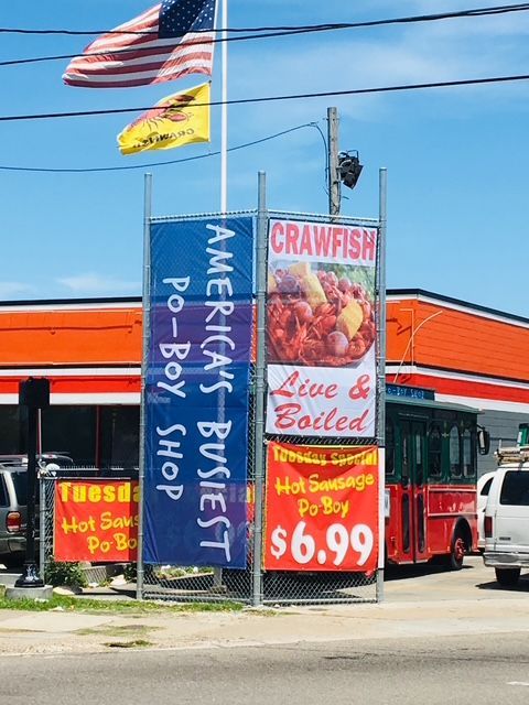 Roadside seafood stand with blue “America’s Best Hot Boil” sign and “Crawfish Live & Boiled” banner.