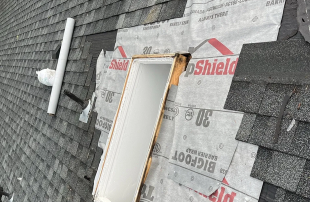 Close-up of roof repair around skylight with exposed underlayment and flashing