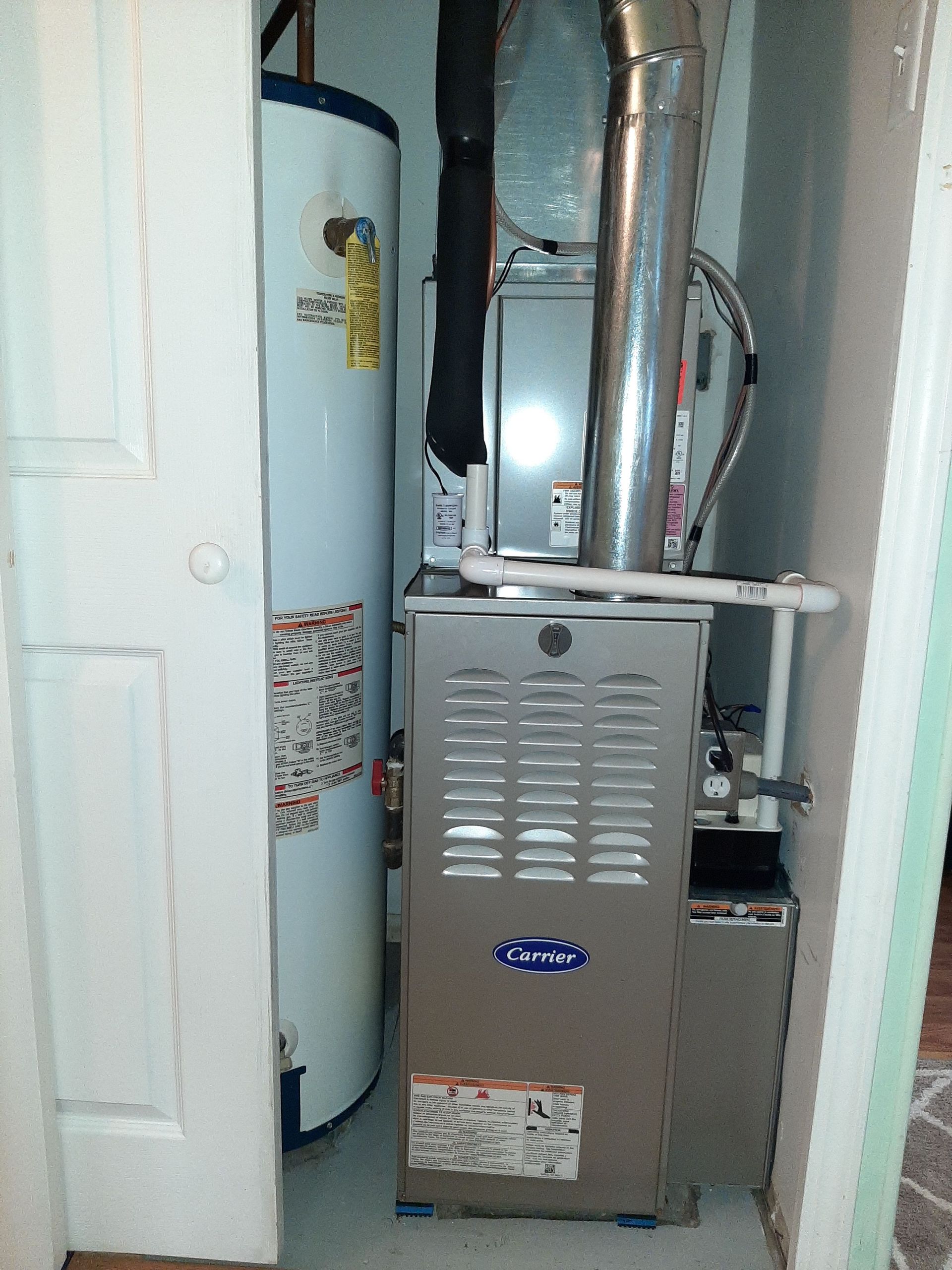 Water heater and furnace in a utility closet with a white door.