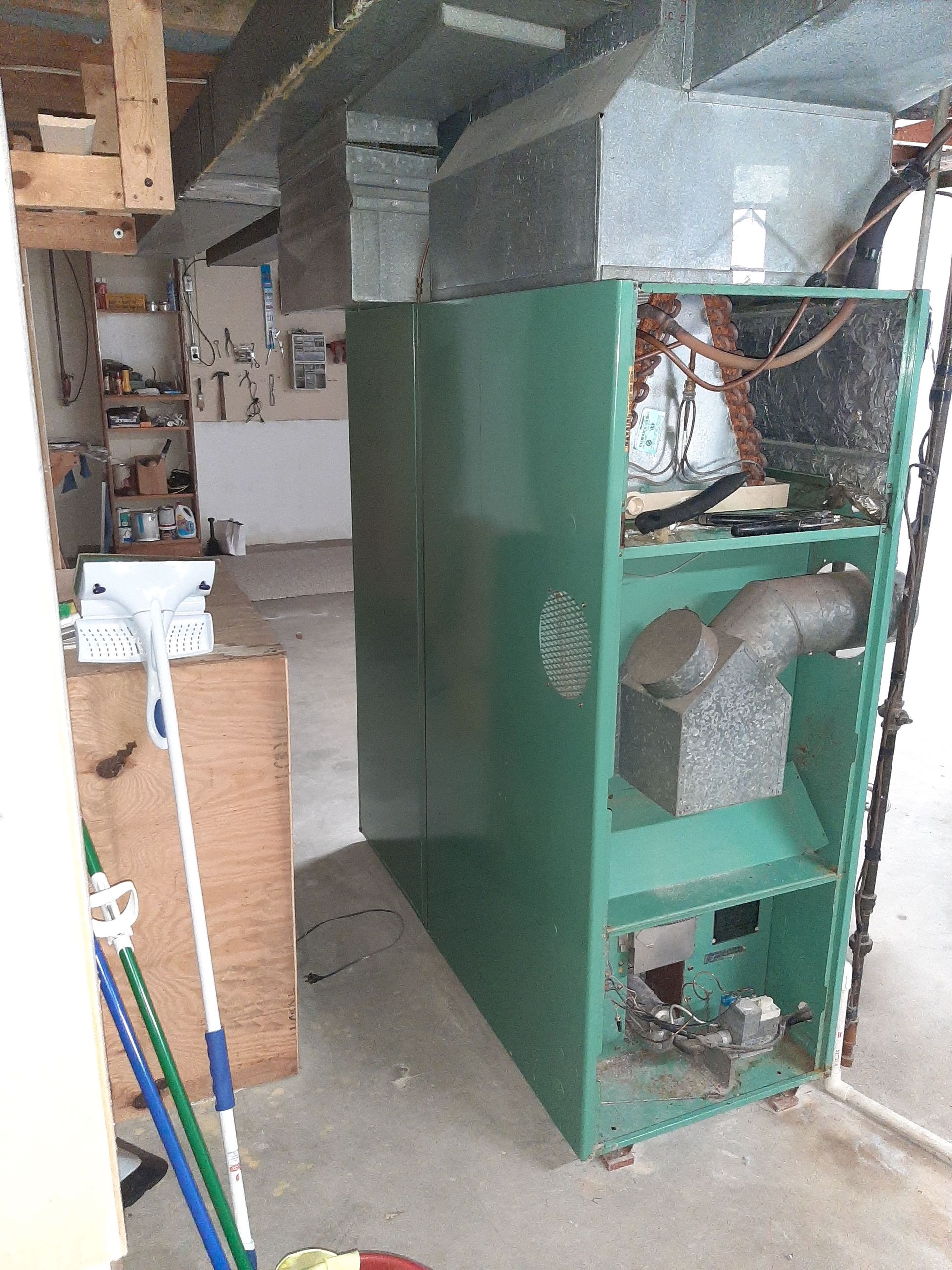 Green furnace in a basement with exposed internal components.
