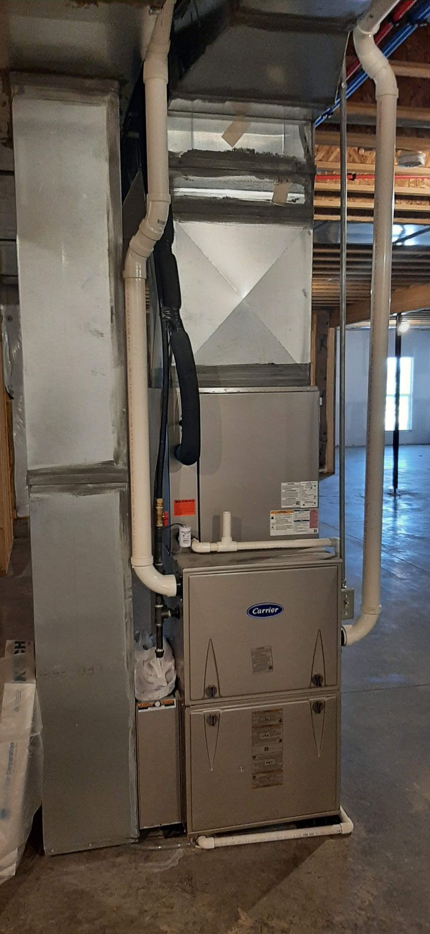 Furnace and ductwork in a basement setting. The furnace is a Carrier model.