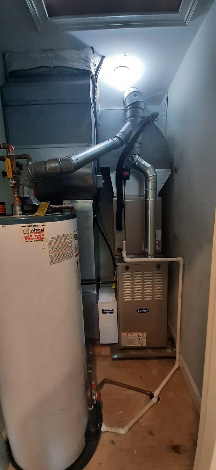 Water heater and furnace in a small utility room. Ductwork and pipes visible.