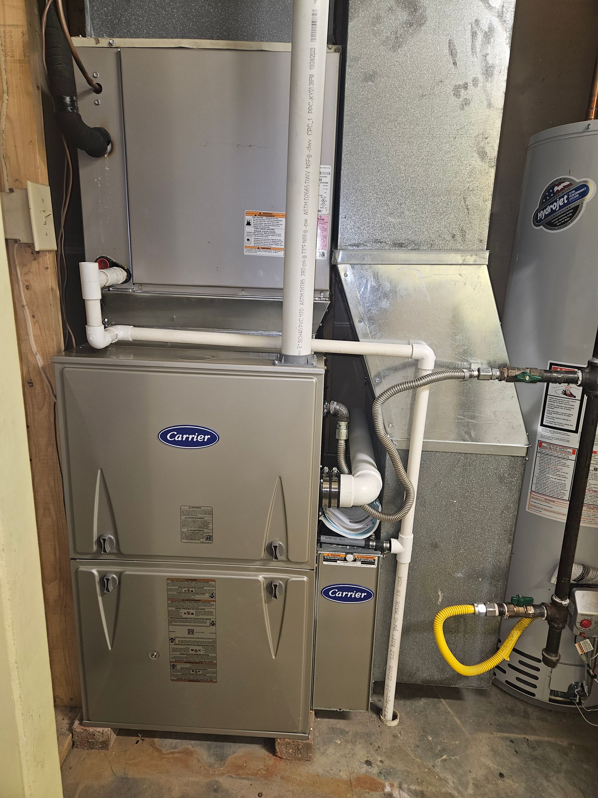 A silver HVAC system with ductwork, a water heater, and gas lines in a utility room.