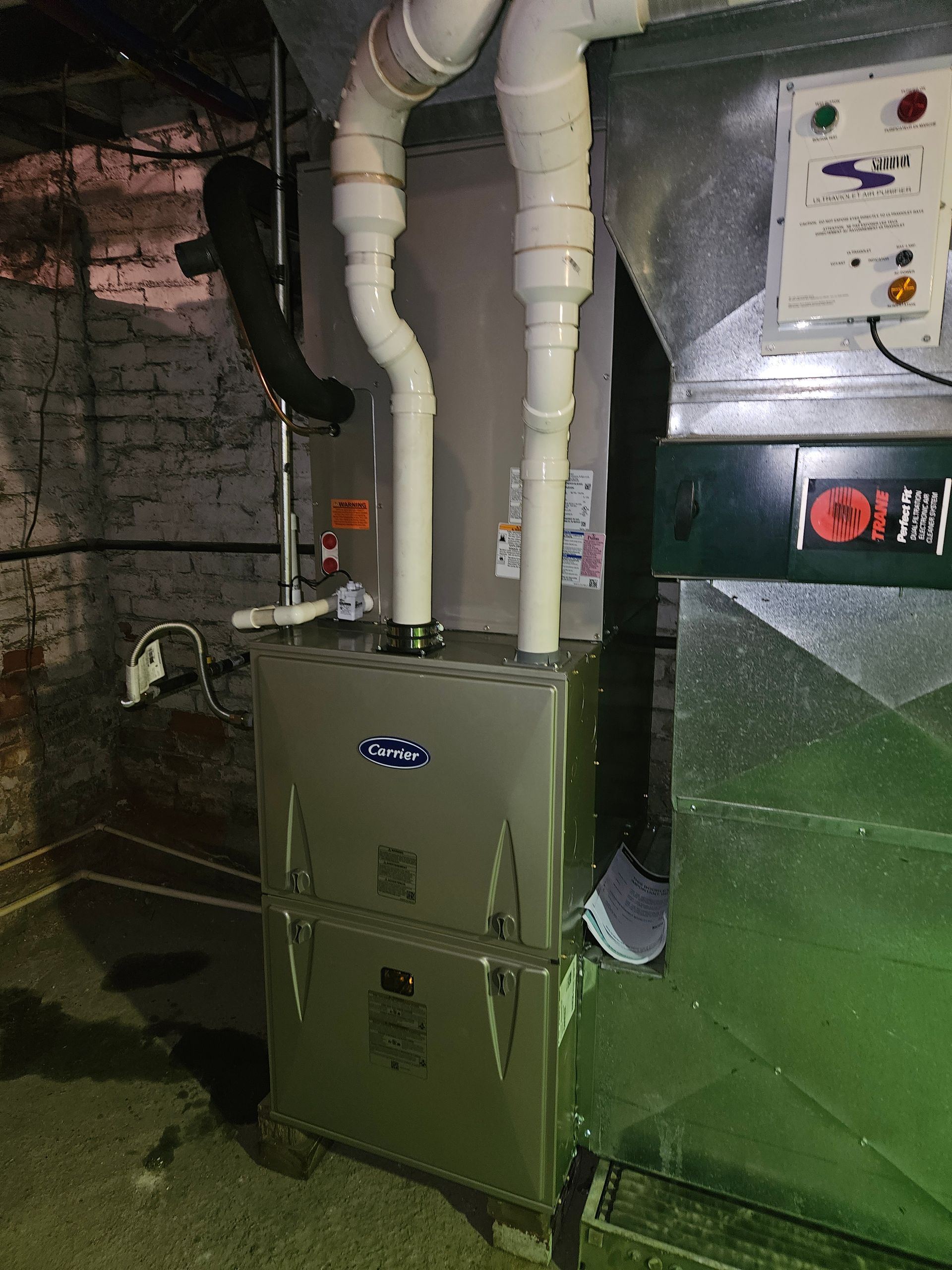 Furnace with white PVC pipes in a basement setting.