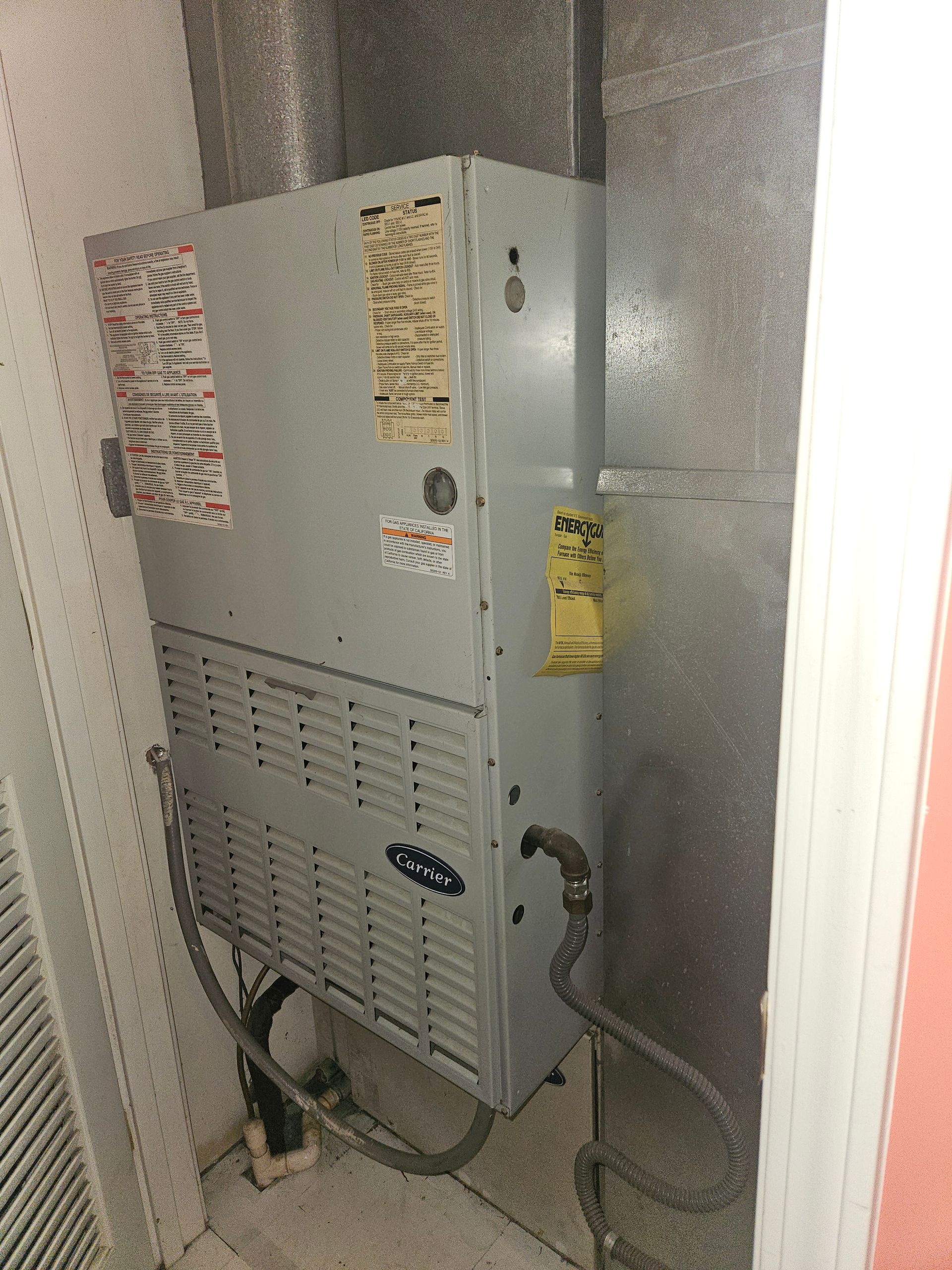 Carrier HVAC unit in a utility closet with ductwork.