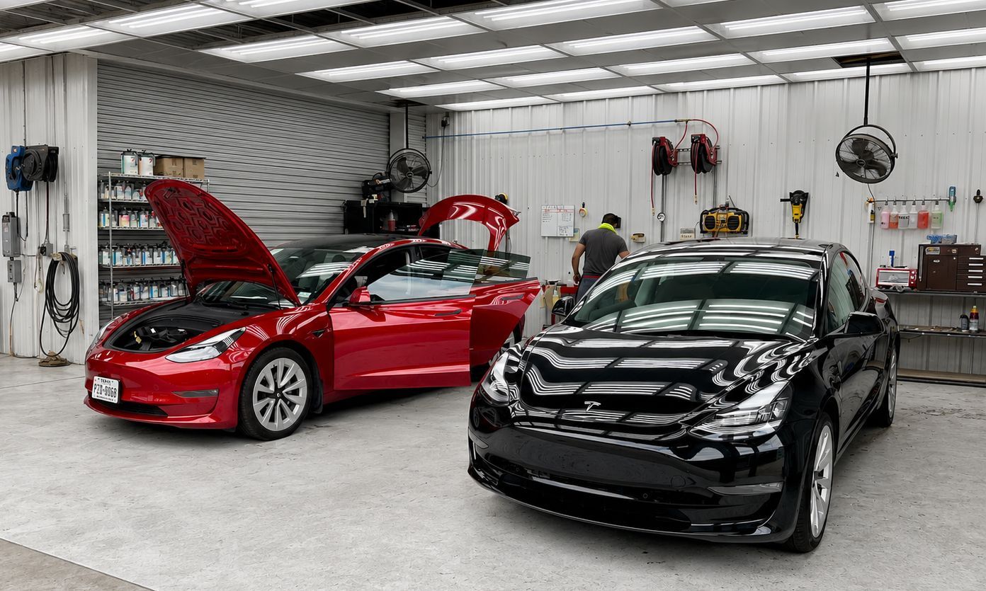 Two electric cars in a garage, one red with hood open and one black in front.