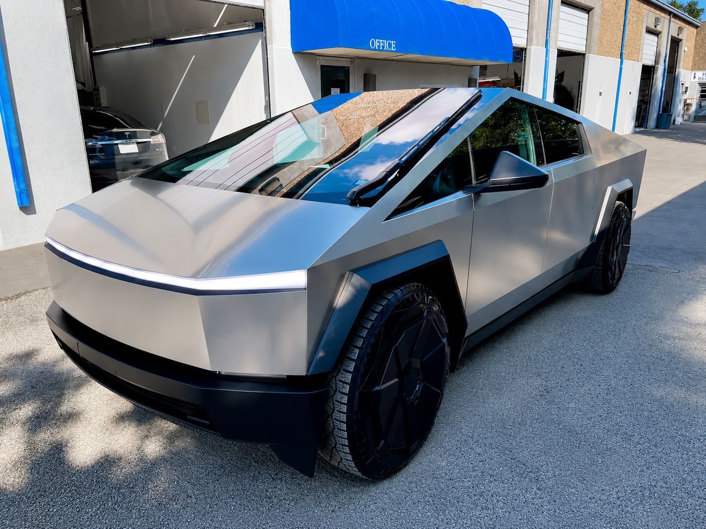 Silver futuristic pickup truck parked outdoors in front of a building