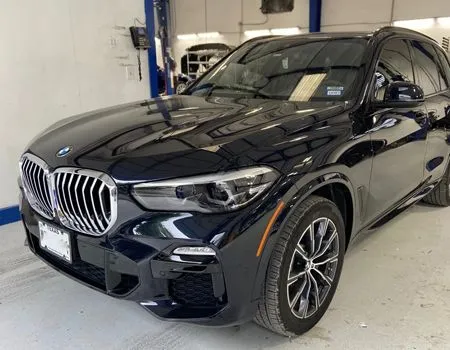 Black BMW SUV in a garage, front-left view.